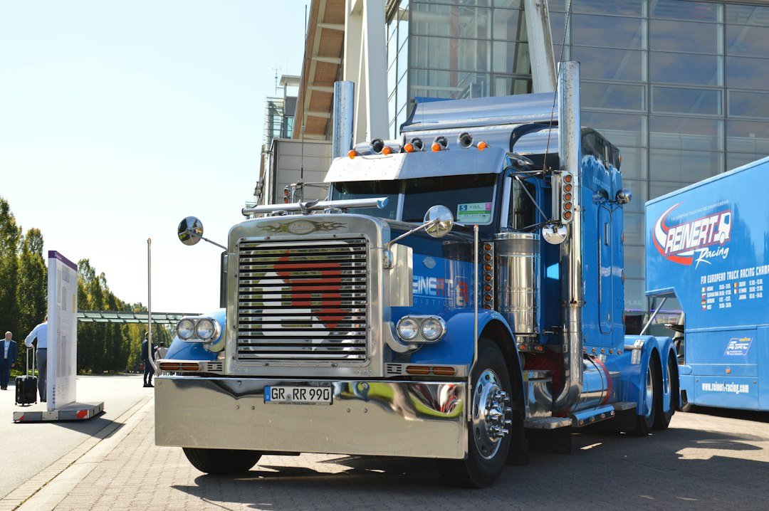 A blue semi truck with chrome accents parked on a paved lot