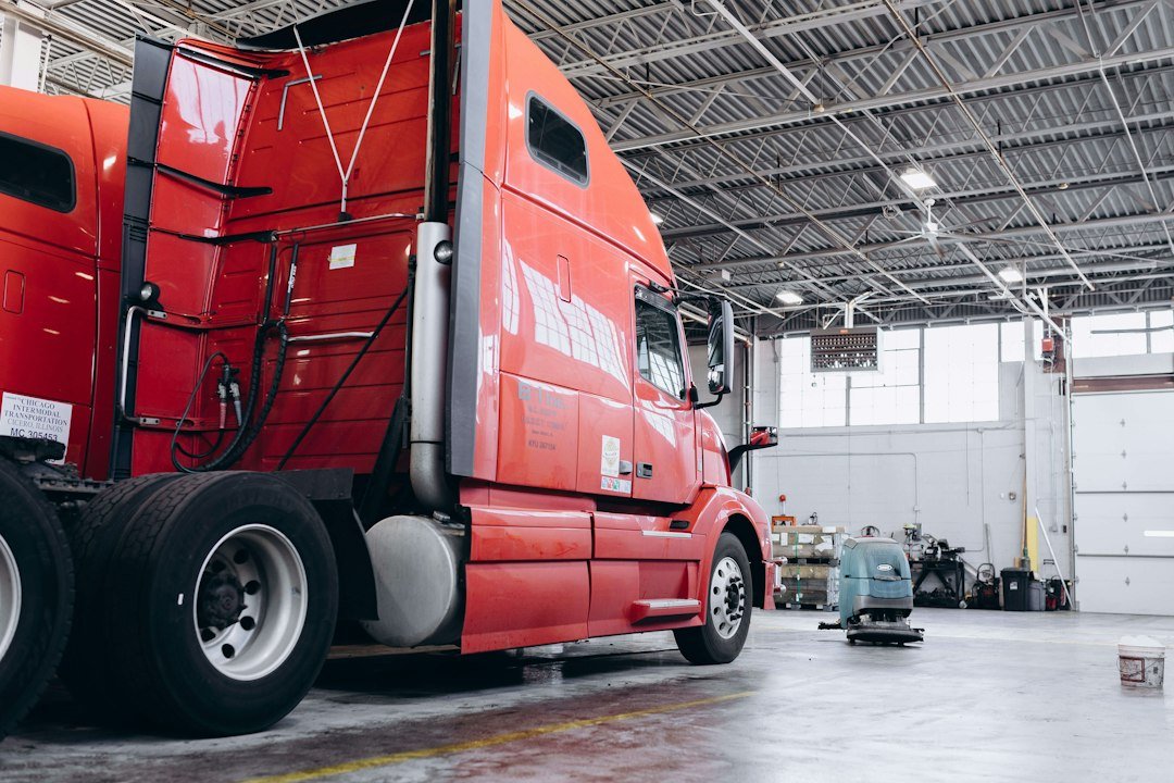 a red semi truck parked inside of a warehouse